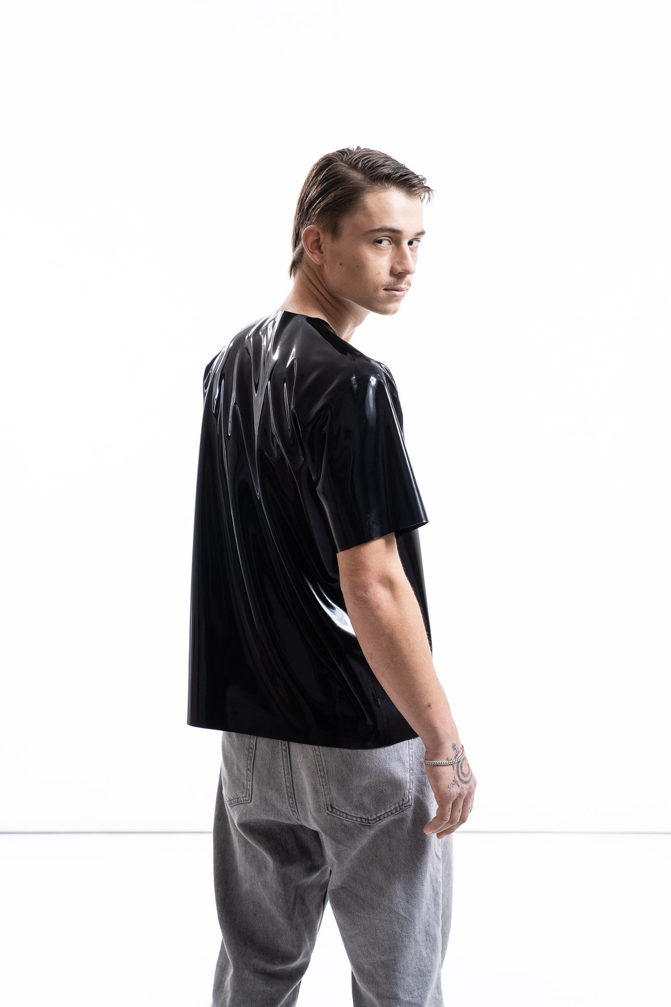 Black latex oversized shirt for men with relaxed silhouette, side detail view